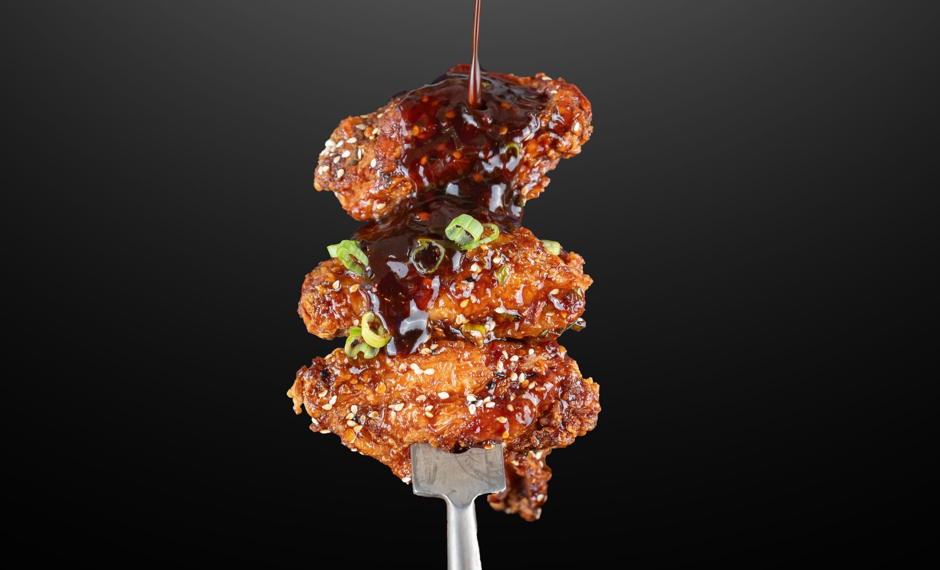 Glazed grilled meat chunks stacked on a skewer against a dark background