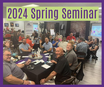 A group of people are sitting at tables at a 2024 spring seminar