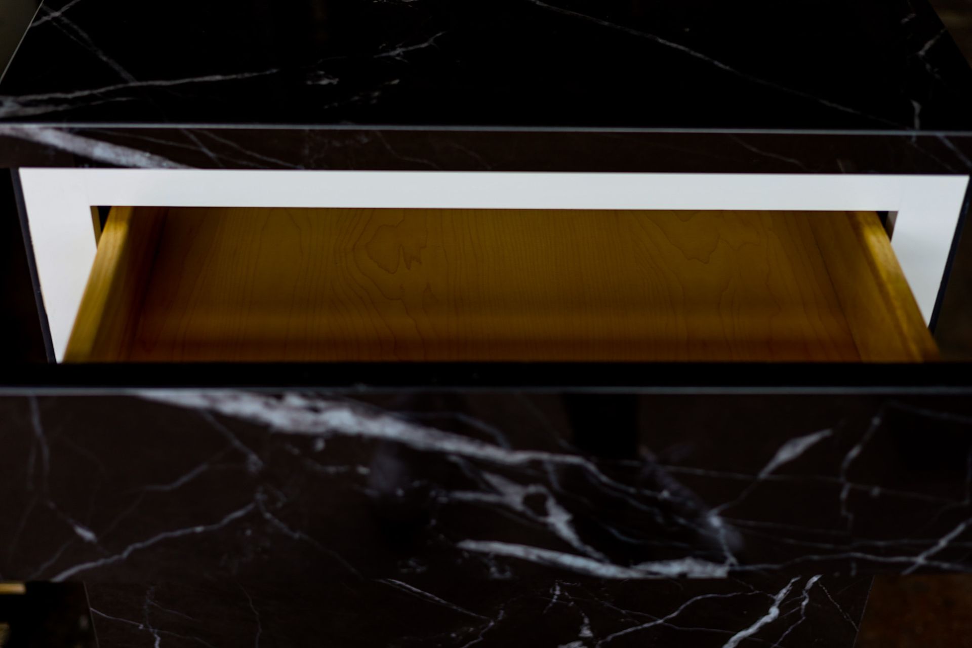 A black and white marble dresser with a gold drawer.
