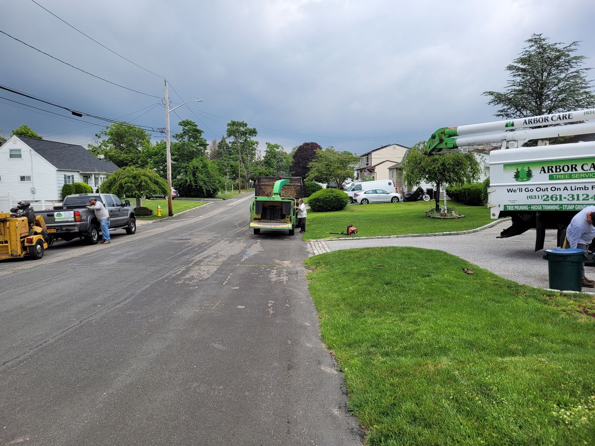 Residential street with utility truck and workers under cloudy sky