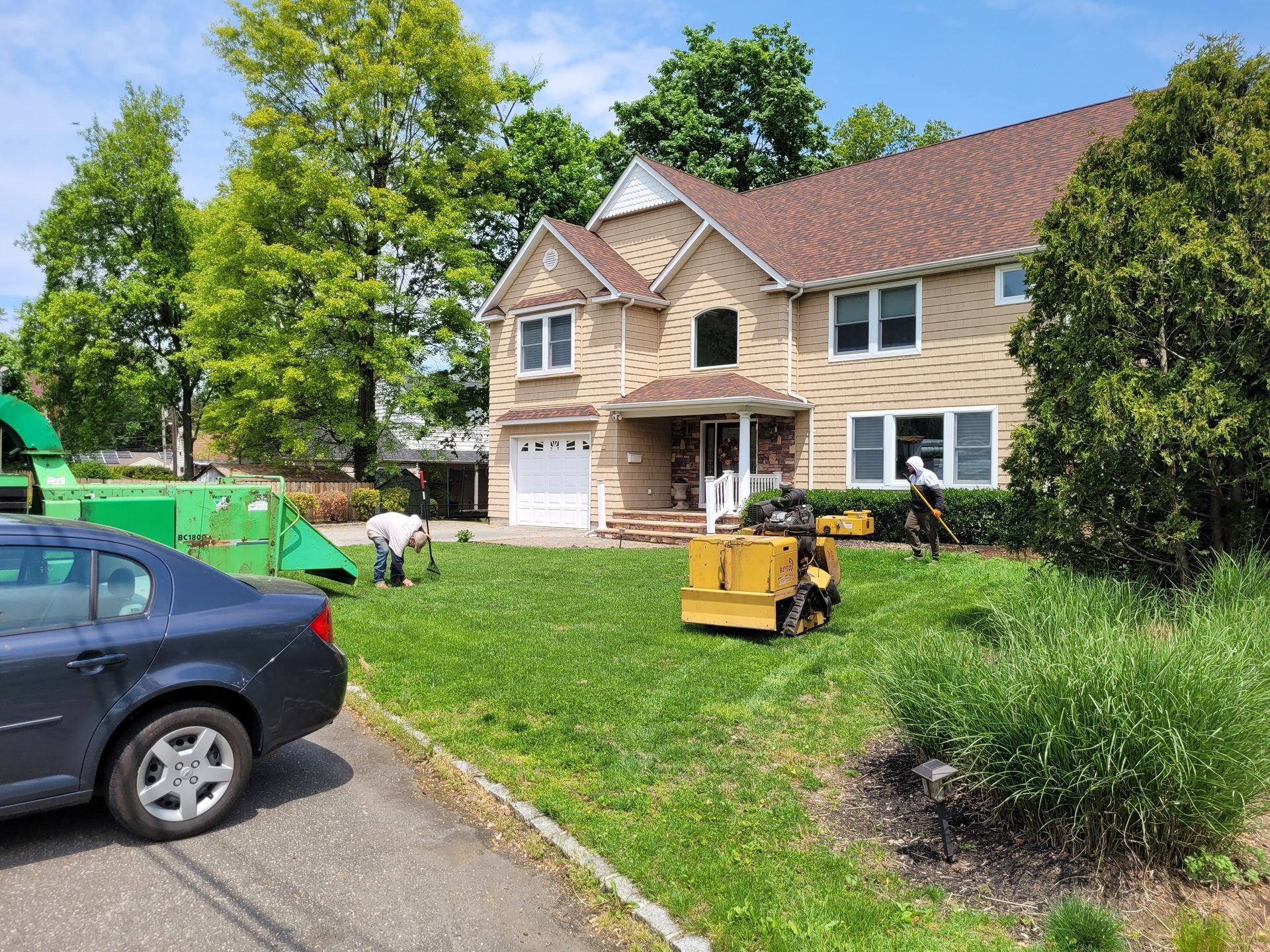Suburban house exterior with workers and equipment on a landscaped lawn under construction