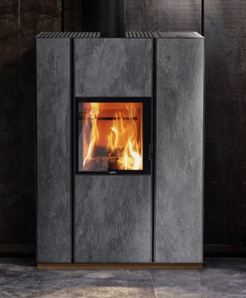 Caminetto moderno grigio a libera installazione con fuoco acceso contro una parete scura.