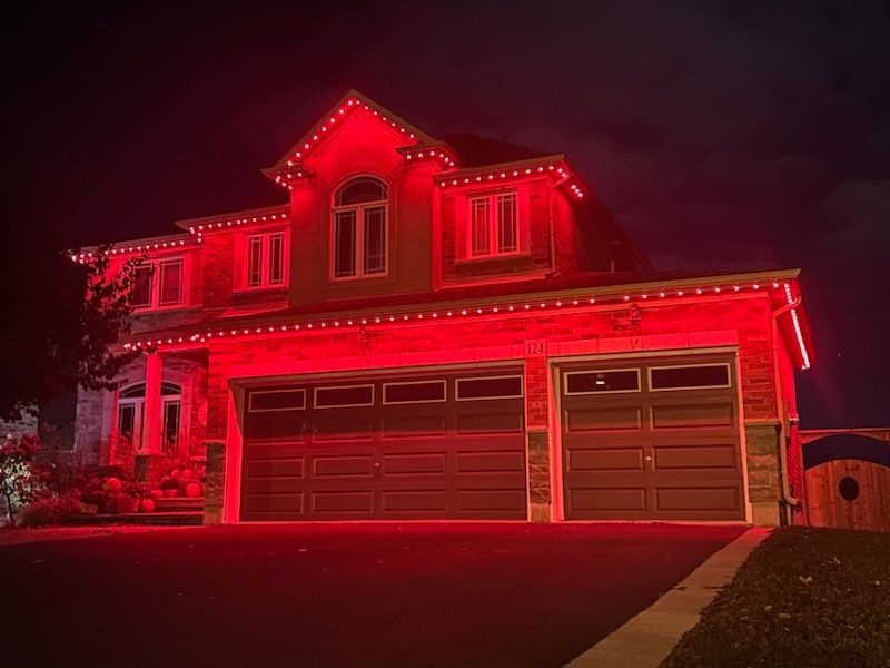 House and garage glowing with red holiday lights at night