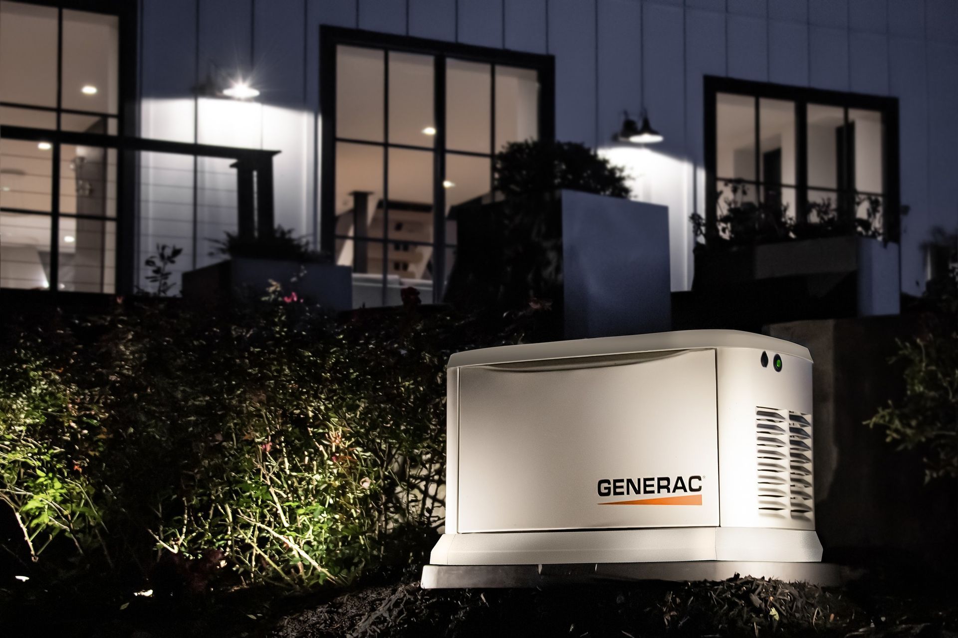 White GENERAL generator outside a lit modern house at night