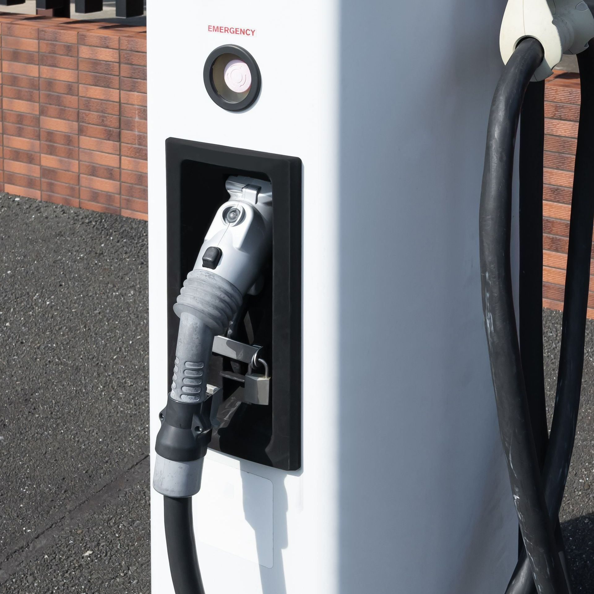 A white electric vehicle charging station with a black hose attached to it.