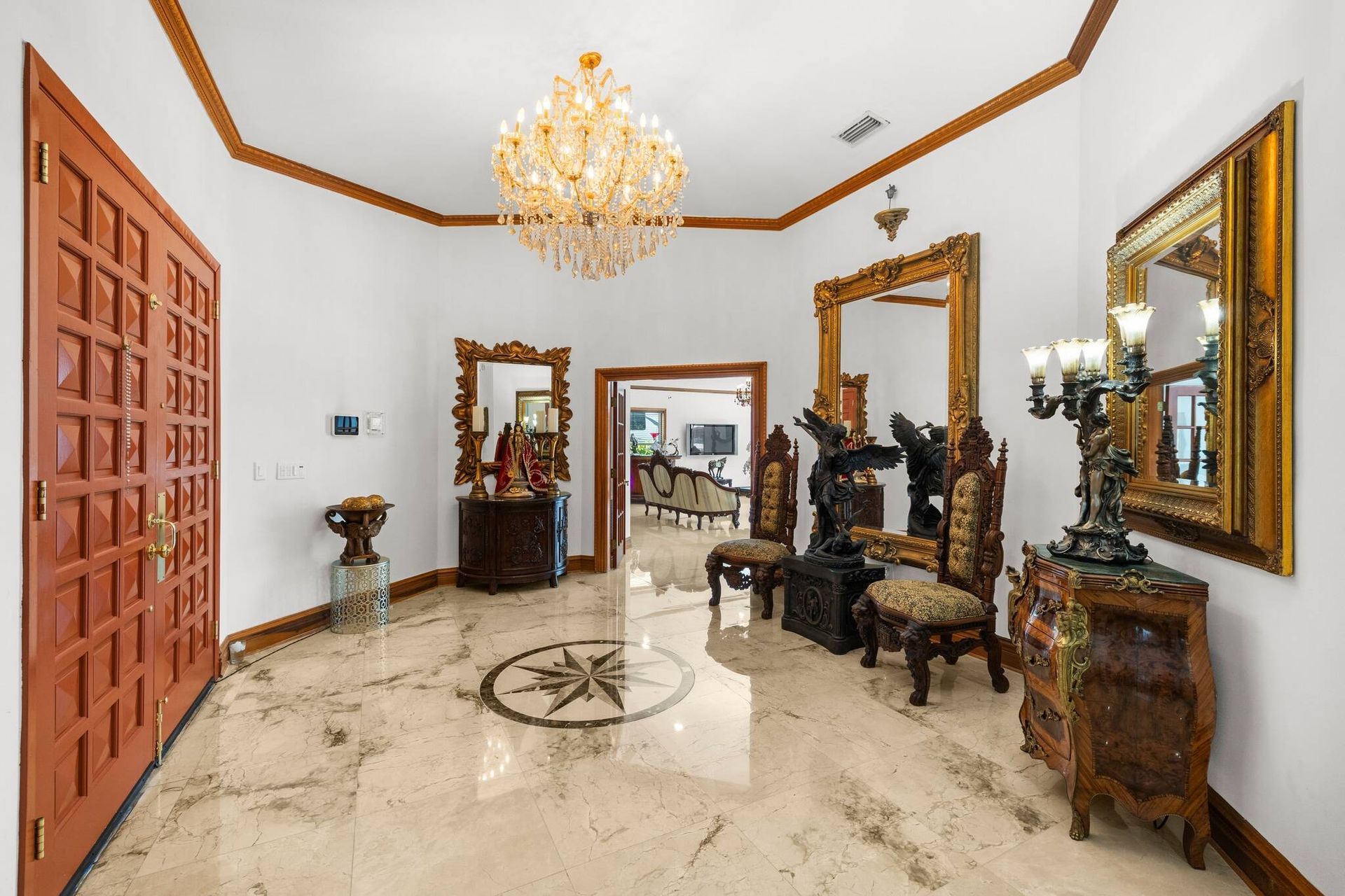 Elegante salón con espejos ornamentados con marcos dorados, muebles tallados y suelos de mármol blanco