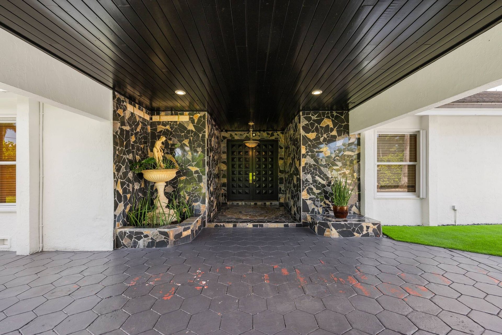 Casa moderna de una sola planta, con una amplia entrada de adoquines, exterior blanco y patio cubierto.