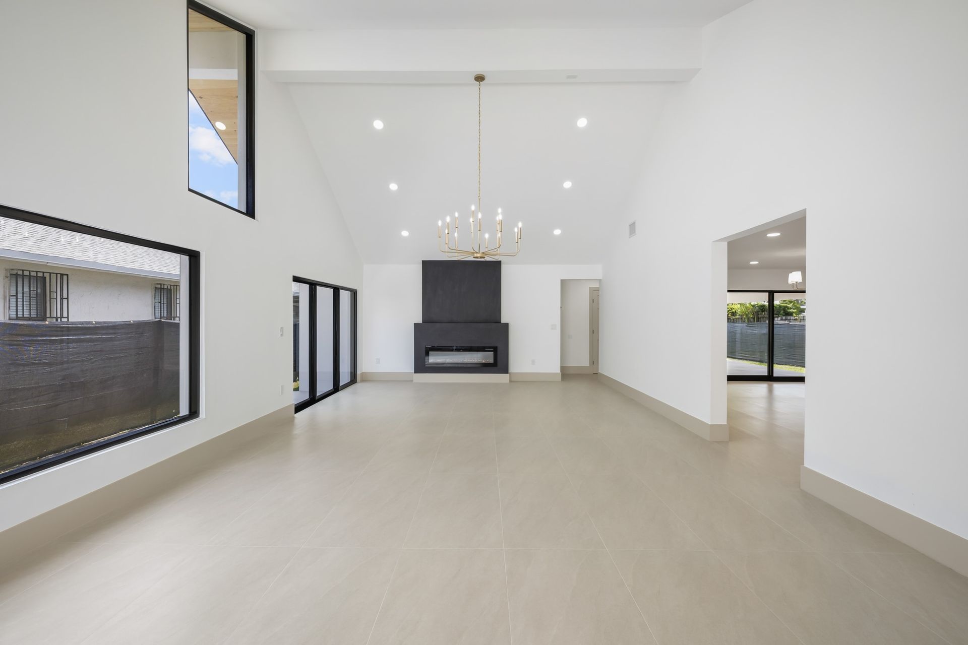 Spacious modern living room with white walls, beige floor, recessed lights, and a fireplace