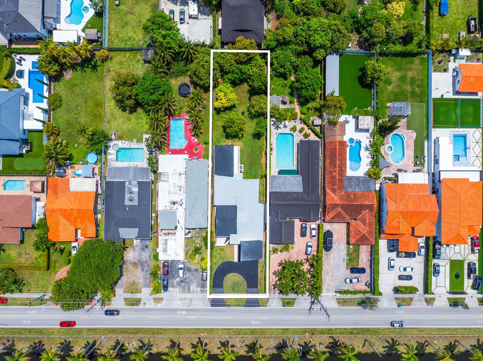 Aerial view of colorful houses with yards and a road along the bottom.