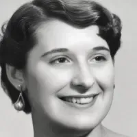 Black-and-white portrait of a smiling person with short hair and earrings