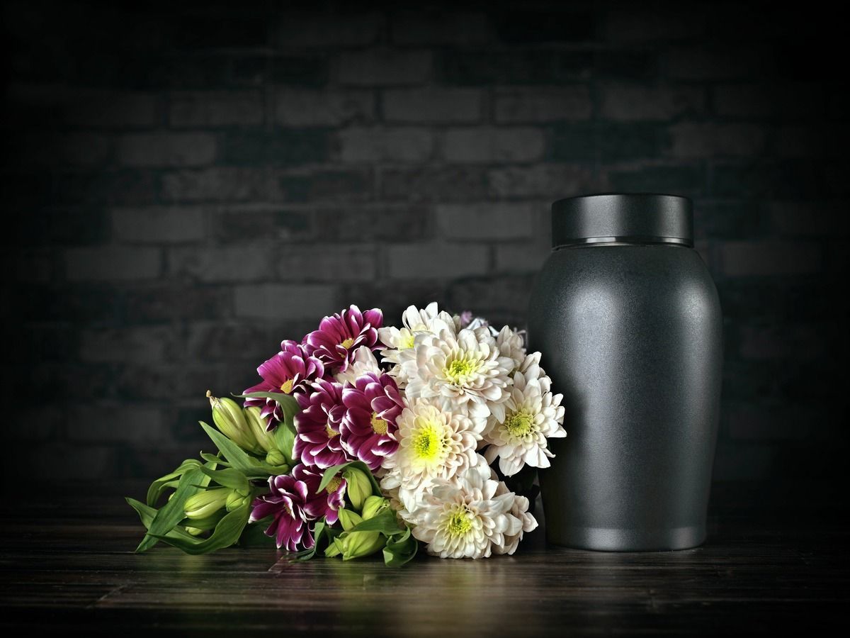 White and purple flowers beside a black vase on a dark stone surface