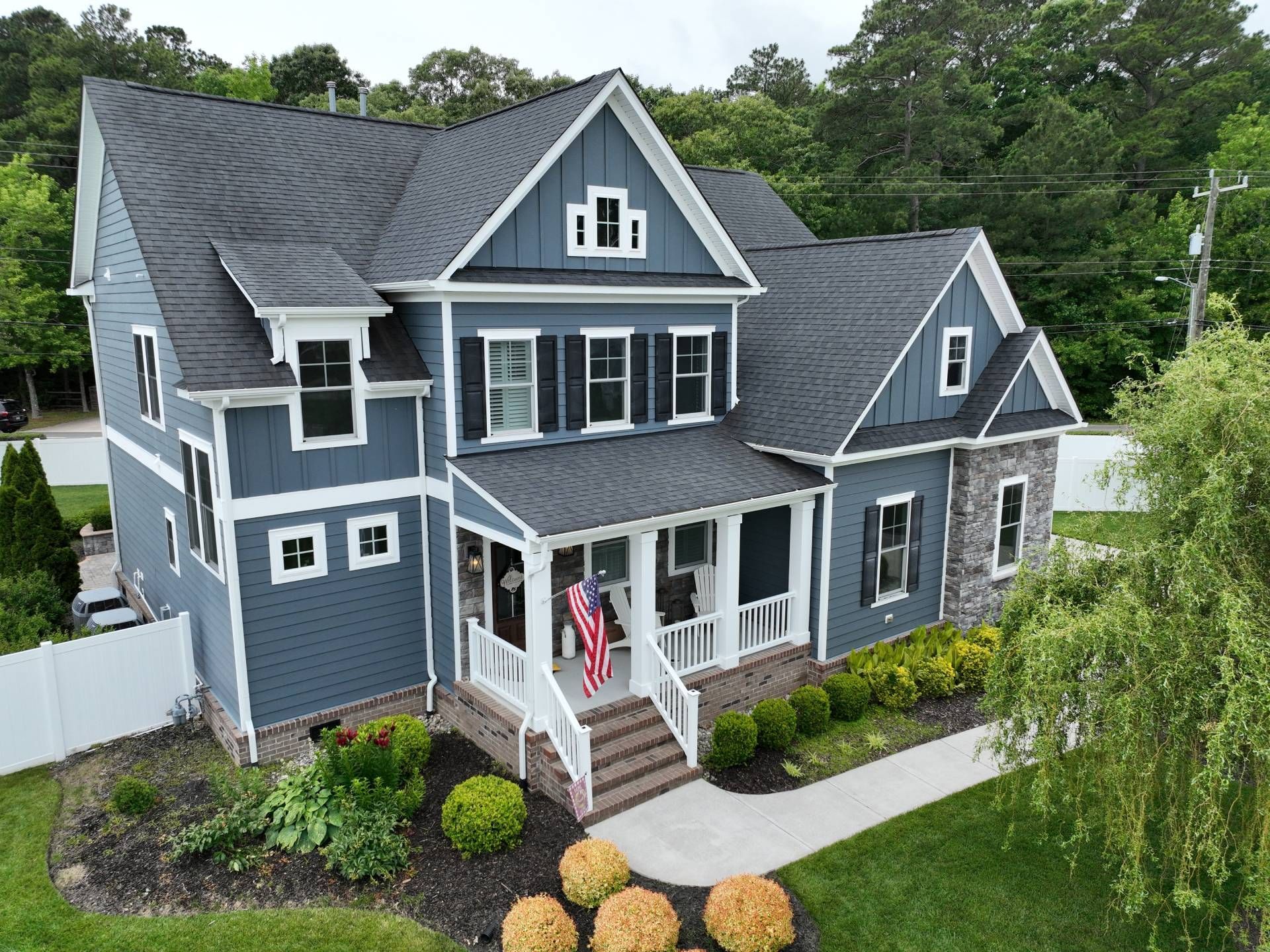 Blue-gray two-story house with white trim, front porch, and landscaped yard