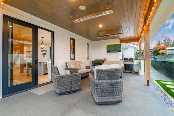 Covered patio with wicker seating, ceiling fans, string lights, and a view of the backyard and pool.