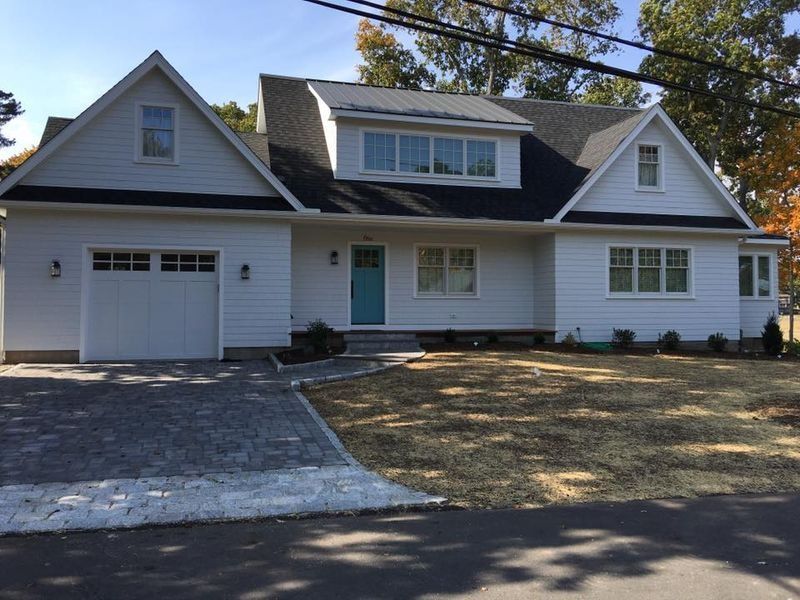 Suburban house with white siding, gray roof, attached garage, and a driveway in front