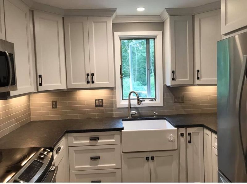 Modern white kitchen with gray countertops, stainless appliances, and a window over the sink