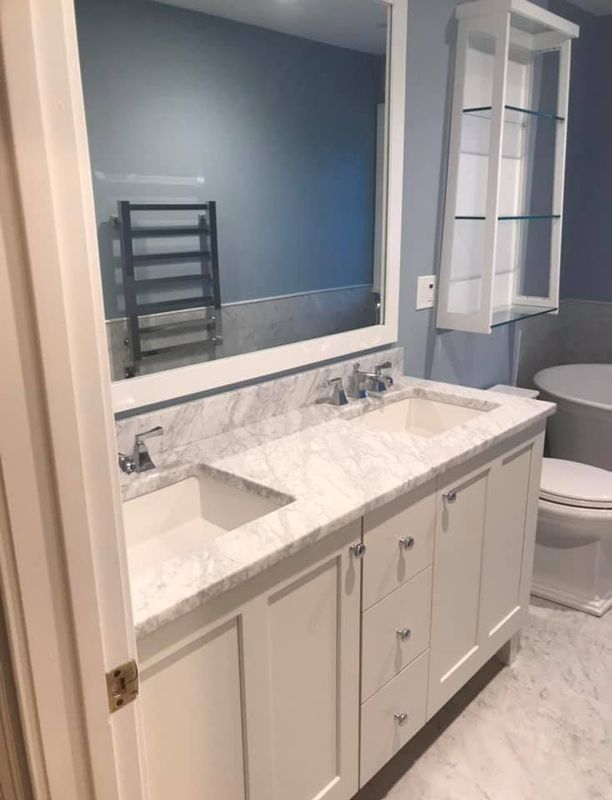 Modern bathroom vanity with white marble countertop, double sinks, large mirror, and blue walls