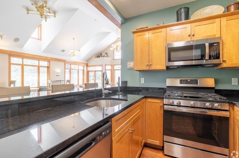 Kitchen with wooden cabinets, stainless steel appliances, black granite countertops, and an island.