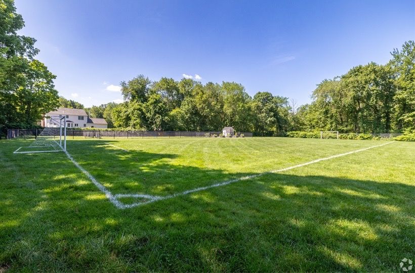 Outdoor community soccer field with white goalposts, green grass, and trees.