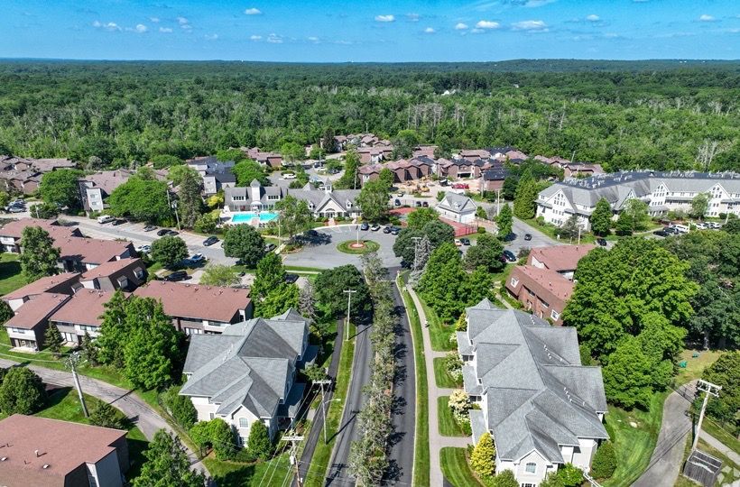 Aerial view of a residential apartment community with multiple buildings, streets, and green trees.