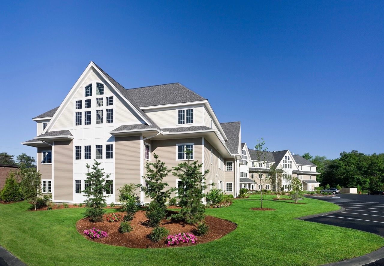 Exterior view of a multi-building apartment complex with a manicured lawn.