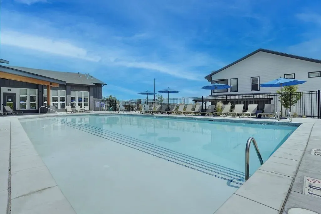 Outdoor swimming pool with lounge chairs and umbrellas at Valley View, offering apartments in Magna, UT.