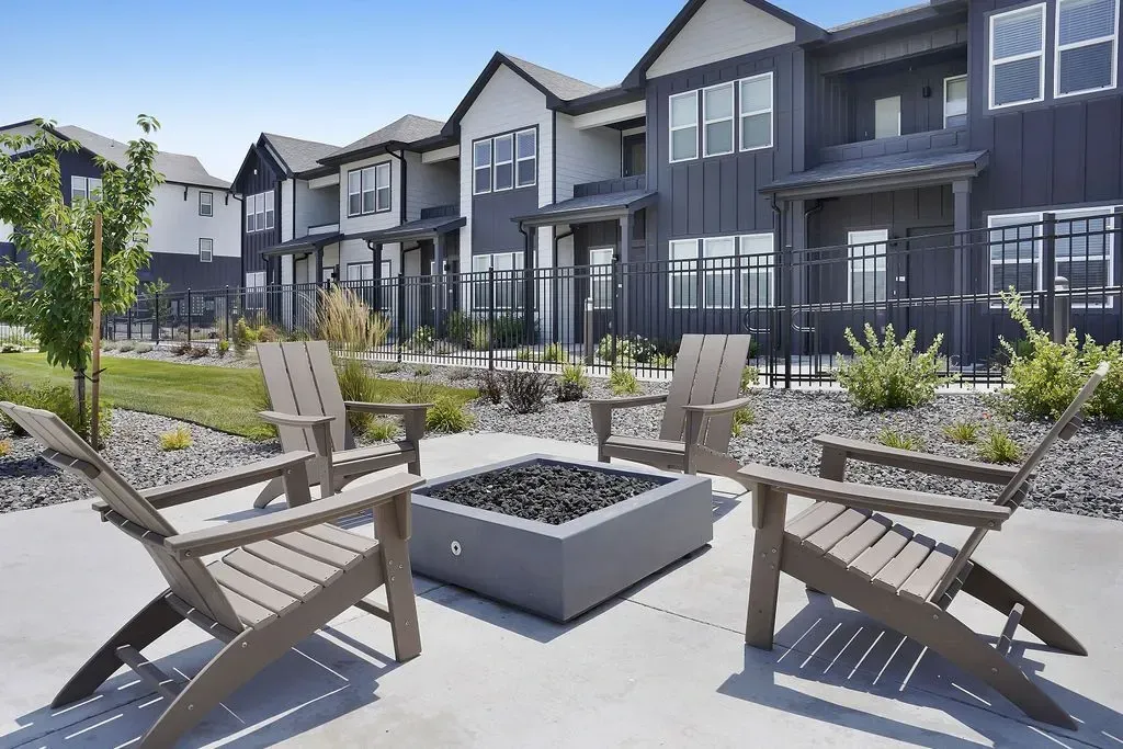 Adirondack chairs around a modern fire pit with apartment buildings in the background at Valley View, offering apartments in Magna, UT.