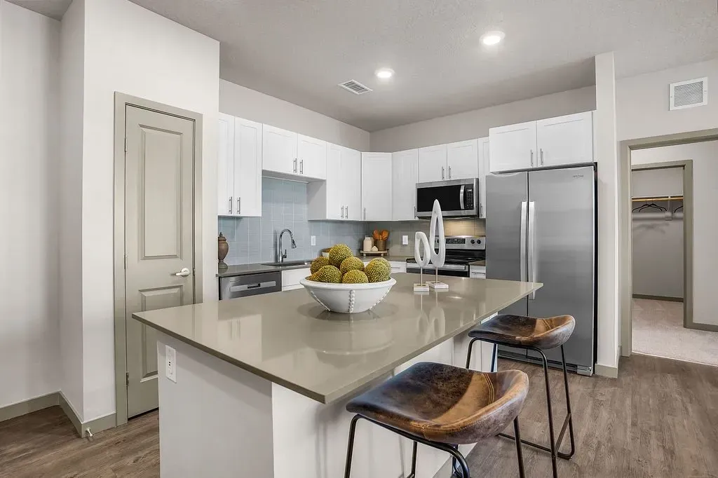 Modern kitchen with island, stainless steel appliances, and breakfast bar seating at Valley View, offering apartments in Magna, UT.