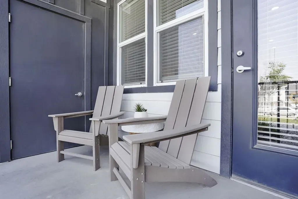 Two Adirondack chairs on a balcony with a small potted plant at Valley View, offering apartments in Magna, UT.
