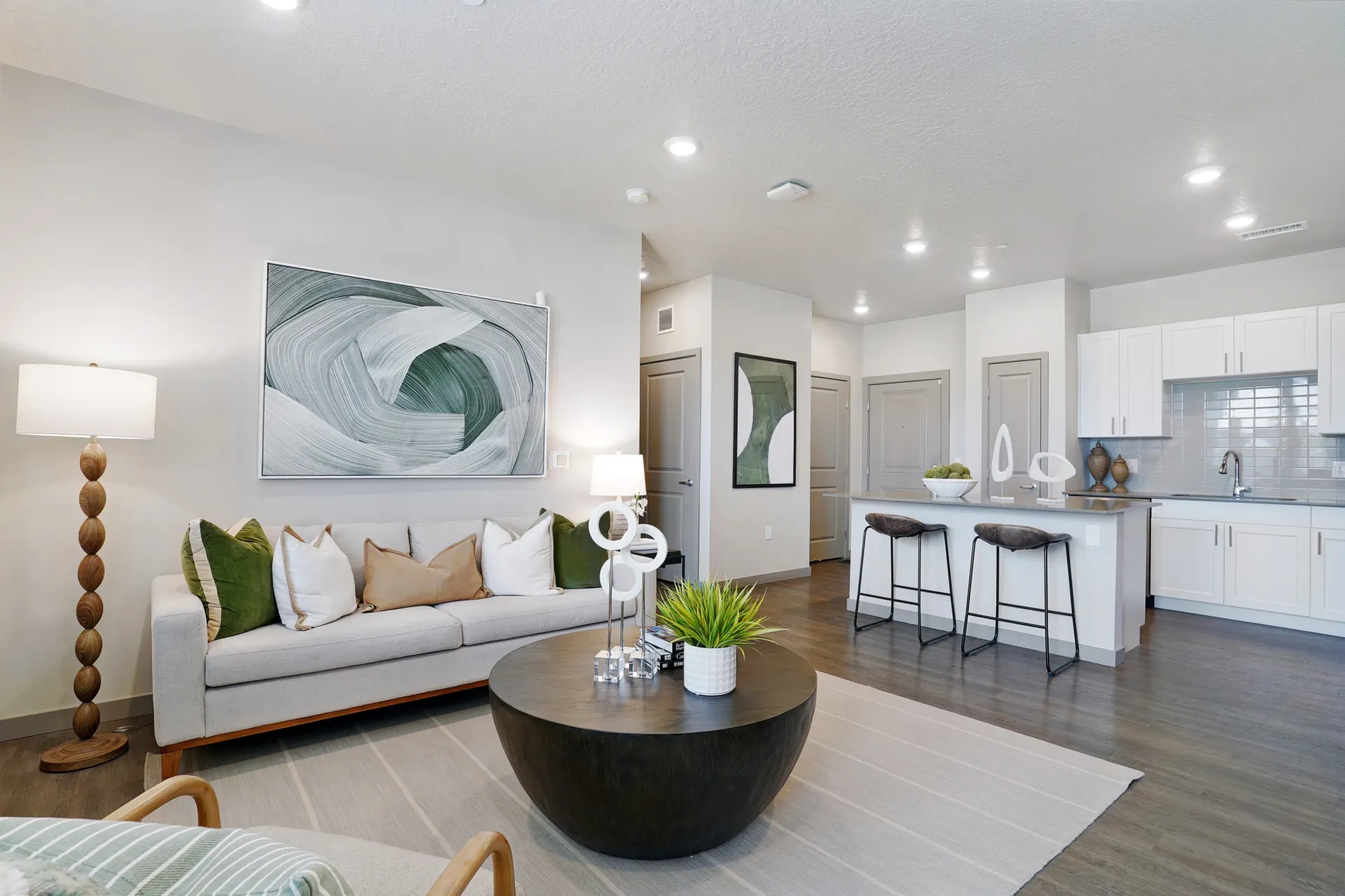 Modern living room and kitchen area with stylish furniture, including a sofa, coffee table, and bar stools at Valley View, offering apartments in Magna, UT.