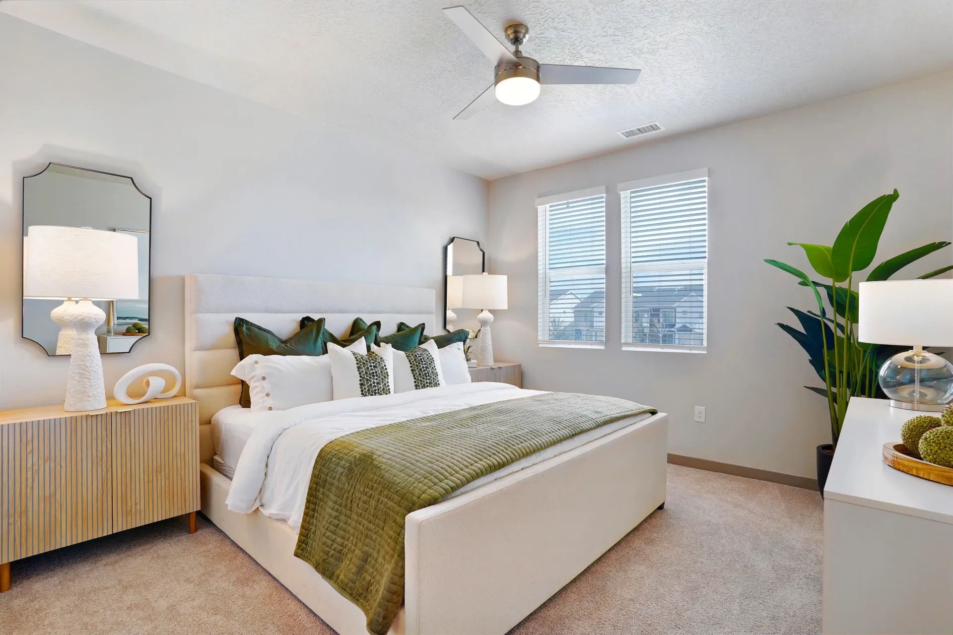 Bedroom with a large bed, nightstands, a dresser, and a ceiling fan at Valley View, offering apartments in Magna, UT.