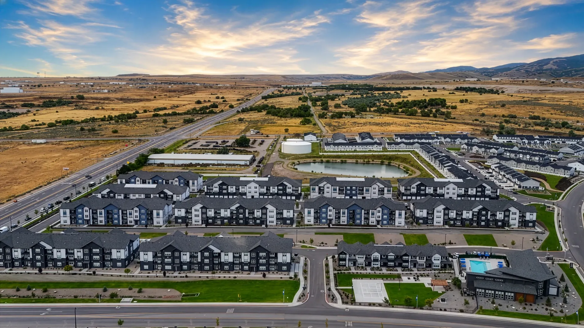 Aerial view of a modern apartment complex with multiple buildings, a pool, and surrounding landscape at Valley View, offering apartments in Magna, UT.