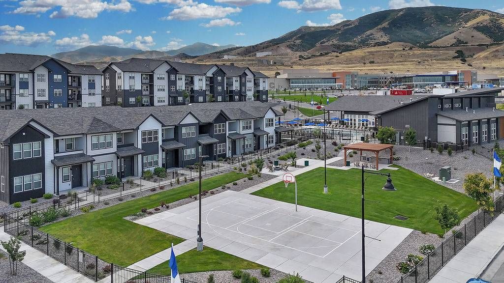 Aerial view of a multifamily community with townhomes, a basketball court, and a green lawn at Valley View, offering townhomes for rent near Salt Lake City.