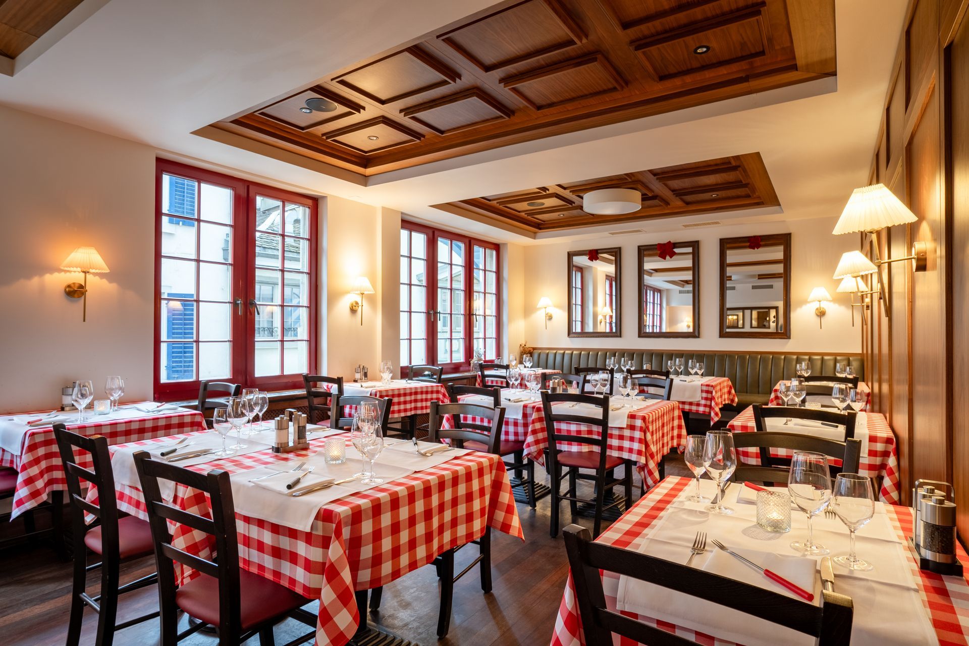 Elegant restaurant dining room with white tablecloths, dark wood walls, and warm ceiling and wall lighting