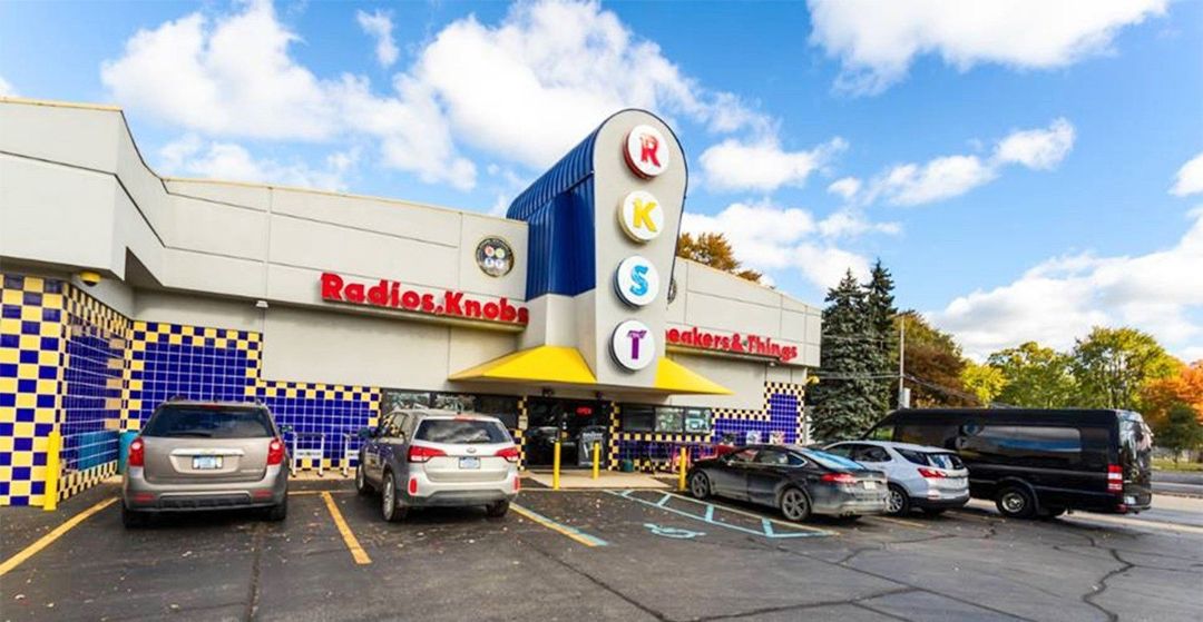 Exterior of "Radio Knob" building with a few cars parked in front.