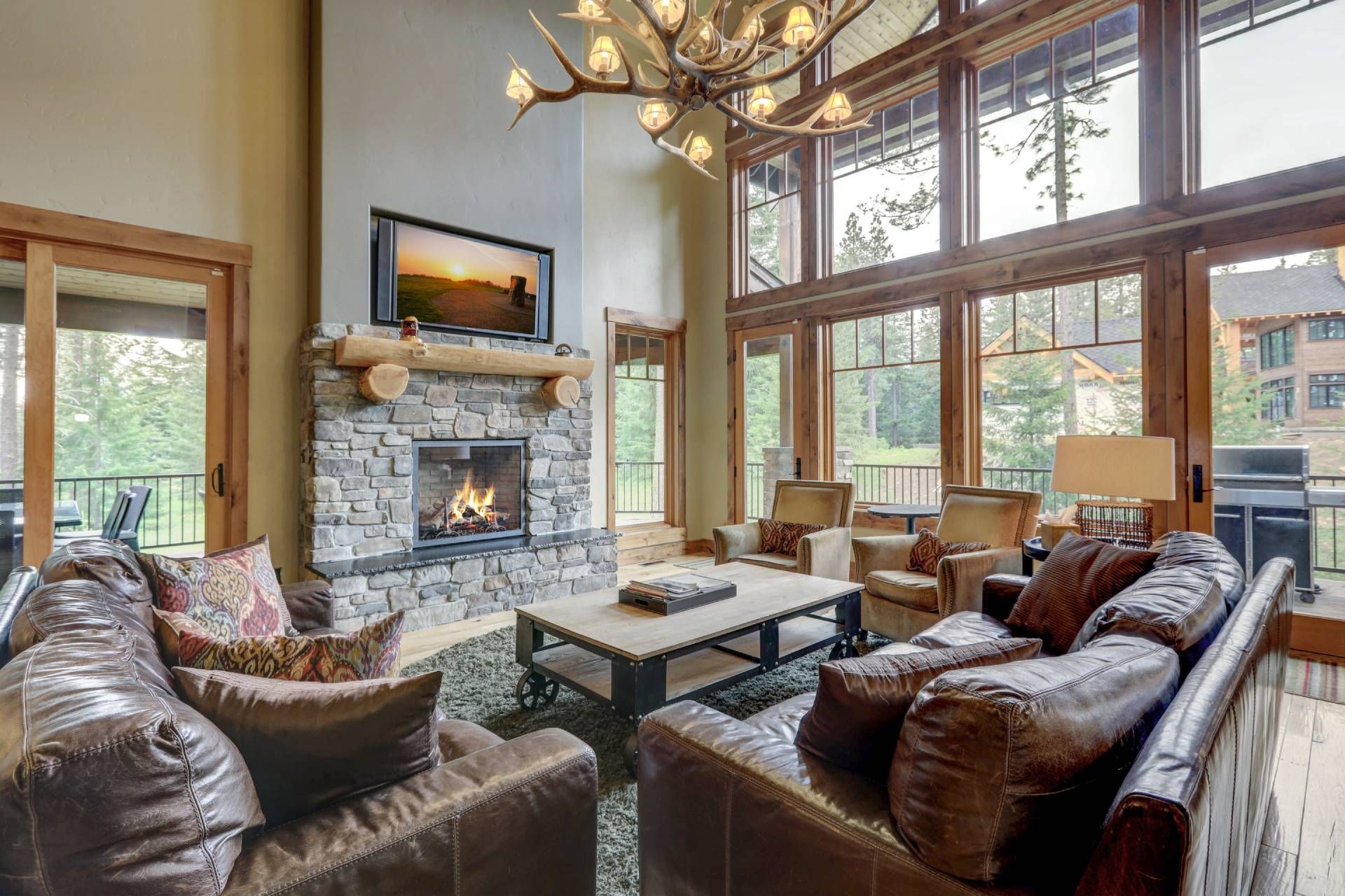 A lodge-style home with high ceilings and floor-to-ceiling windows in need of rustic window treatmen