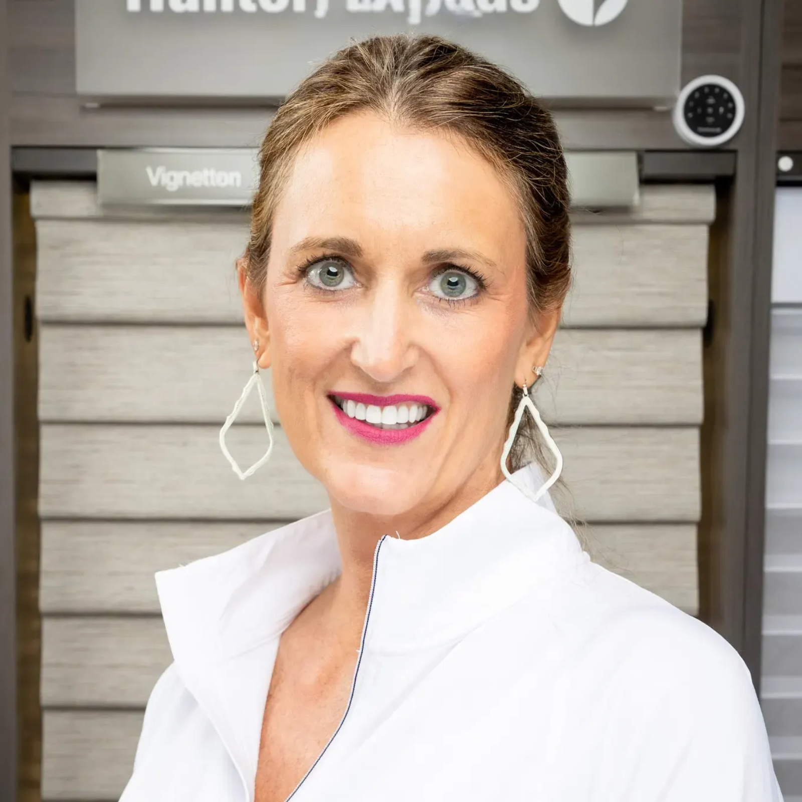 Smiling woman in a white blouse standing in front of a Vignette hair-color display
