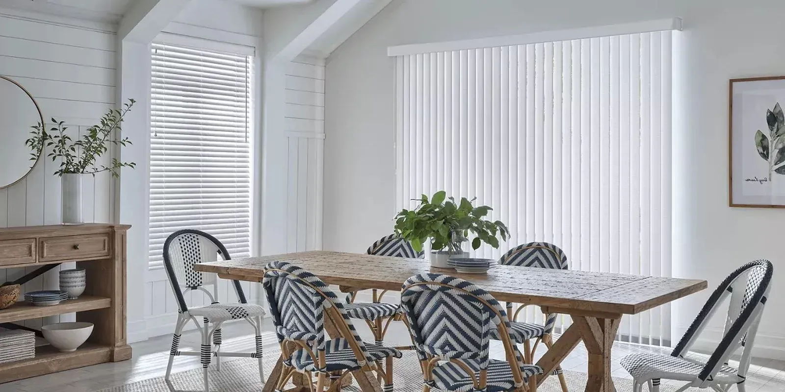 Bright dining room with a wooden table, patterned chairs, and large windows with blinds.