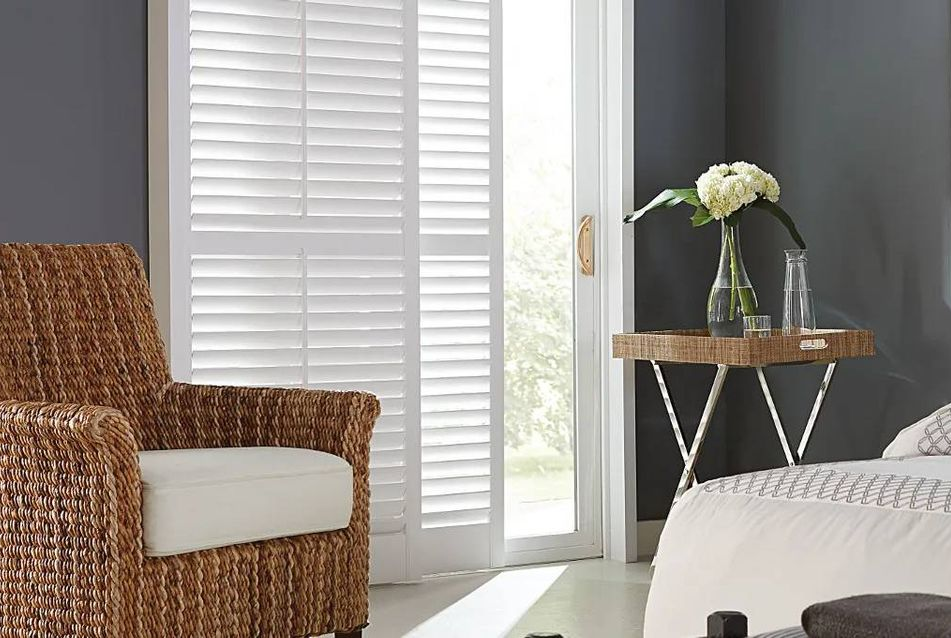 Graber® Composite Shutters on a sliding glass door and window in a bright and airy bedroom