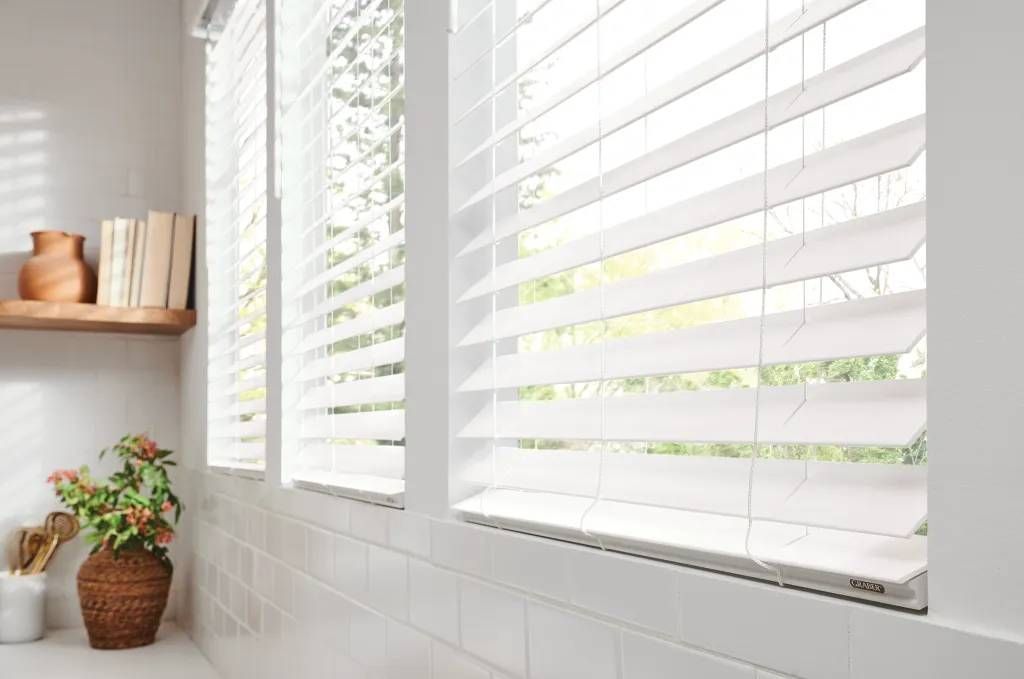 Graber® Faux Wood Blinds in a white color on a kitchen window