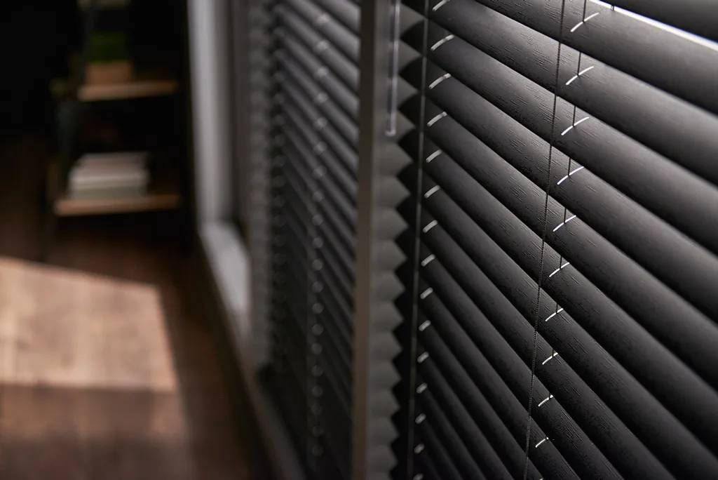 Horizontal Graber® Vinyl Blinds in a moody charcoal hue on windows in a home