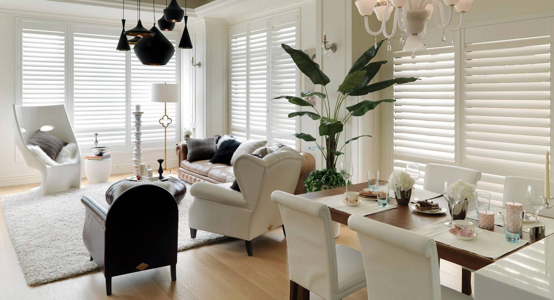 Norman® Woodlore® Shutters on several windows in a living room and dining room
