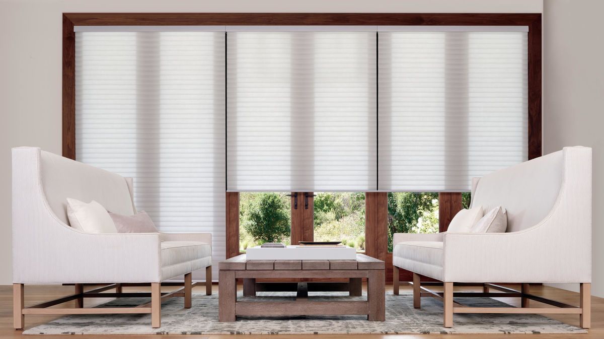 Modern sitting room with two white armchairs, coffee table, and large window blinds