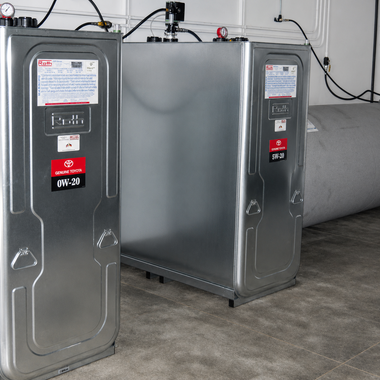 Two gray utility tanks with red labels and black control panels in a garage or basement.
