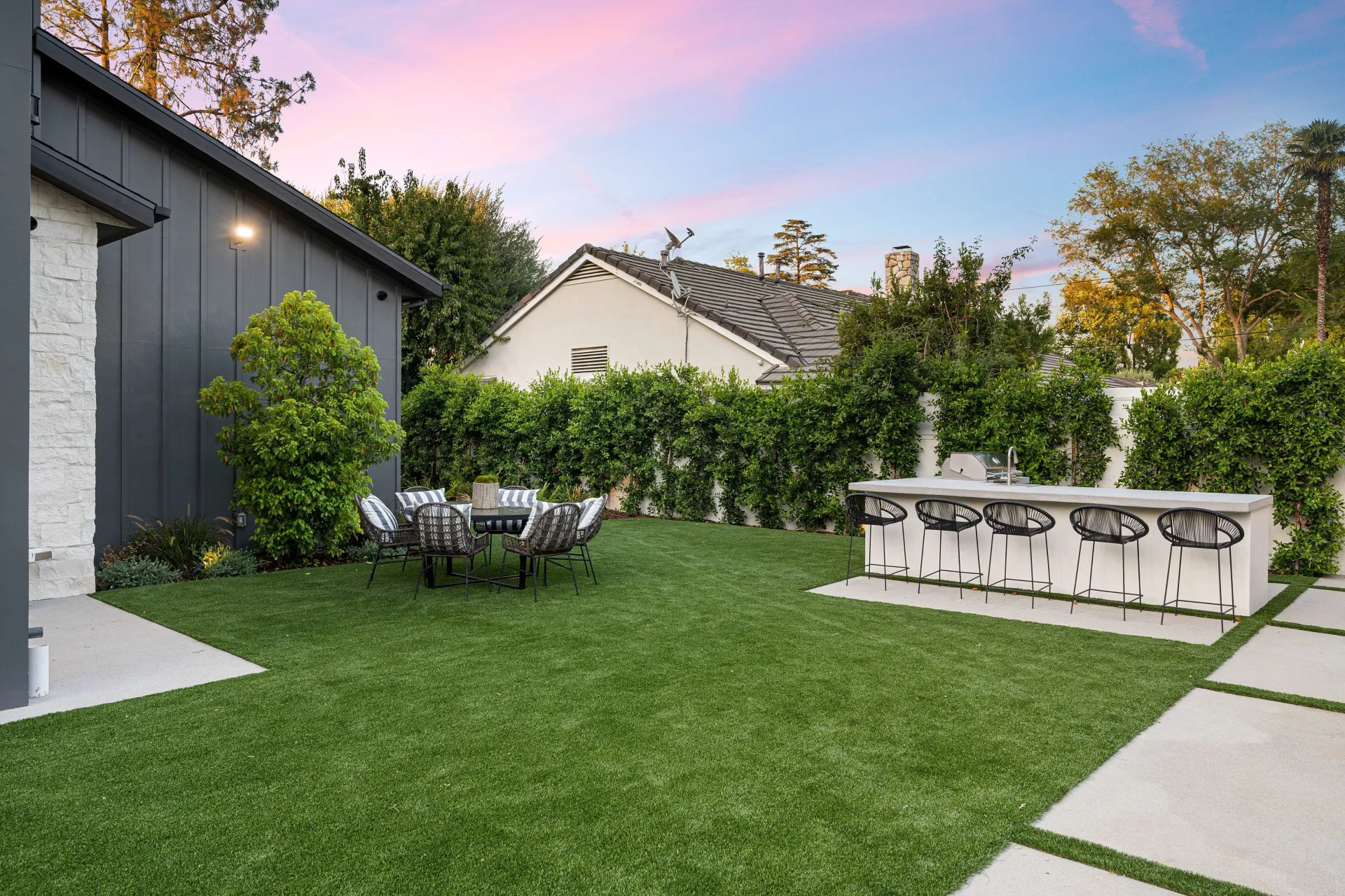 A lush green lawn with a table and chairs in the backyard of a house.