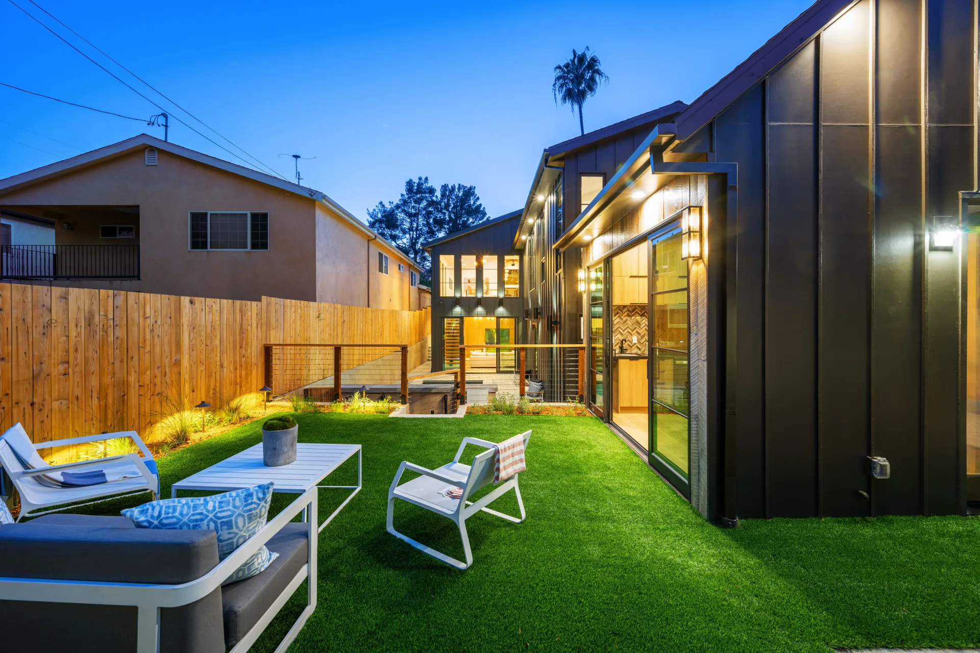 A backyard with a couch and chairs in front of a house.