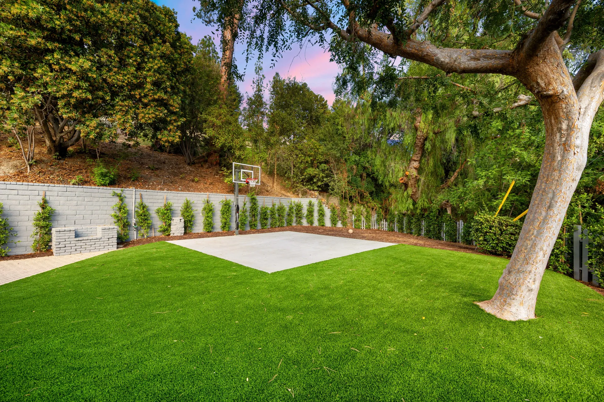 A large lush green lawn with a tree in the middle of it.