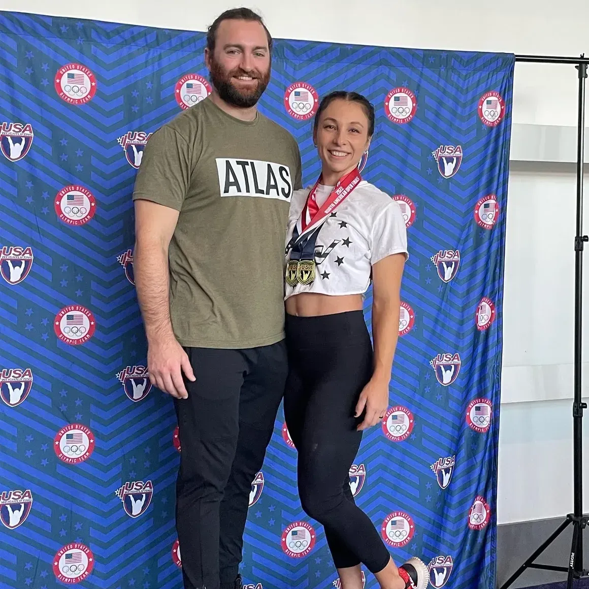 Two medal-winning athletes posing in front of a blue event backdrop