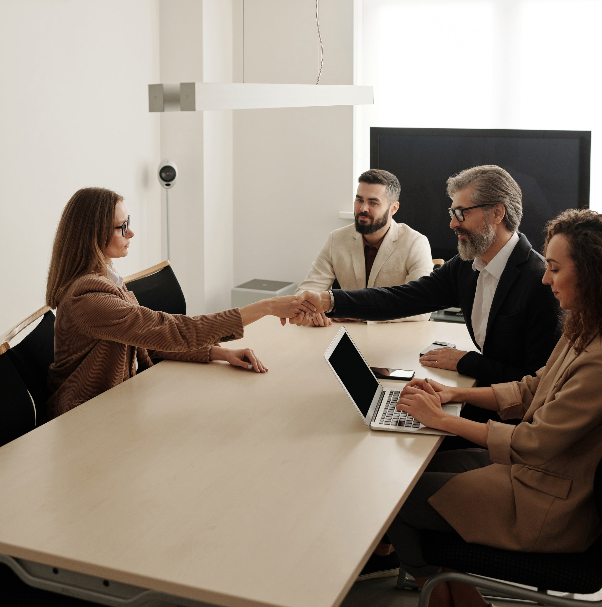 MAN AND WOMAN SHAKING HANDS AT A BUSINESS MEETING