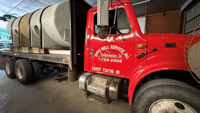 Red truck with large tanks, parked in a garage. "Apple Bell Service, Inc." is visible on the truck.