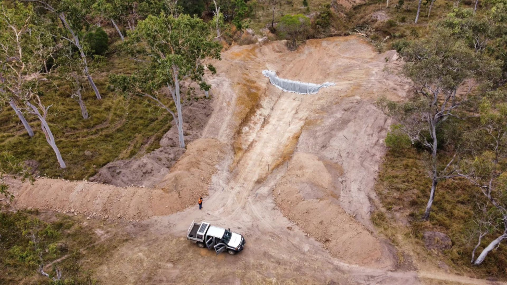 Aerial view of earthworks with a truck and a person near a cleared area in a forest— Macca's Dynamic Earthworks in Tolga, QLD